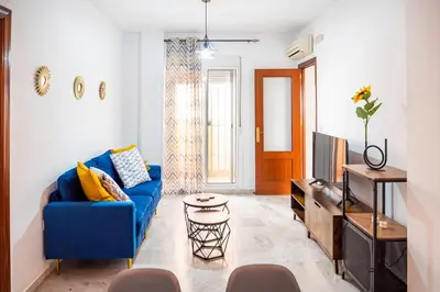 a living room with a blue couch and a tv at Apartamento AGUAMAR in Sanlúcar de Barrameda