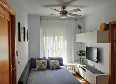 a bedroom with a blue bed with a ceiling fan at Apartamento centro Rota. 2 minutos de la playa.. in Rota