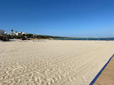 a sandy beach with a wooden boardwalk and the ocean at Apartamento centro Rota. 2 minutos de la playa.. in Rota