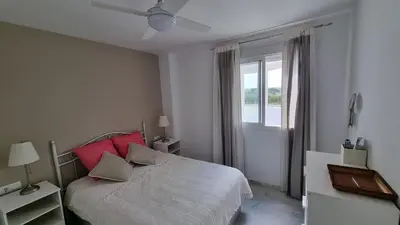 a bedroom with a bed with red pillows and a window at Apartamento Retama Golf in Chiclana de la Frontera