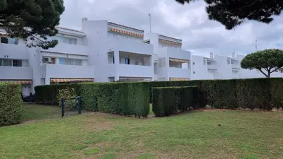a white building with a hedge in front of it at Apartamento Retama Golf in Chiclana de la Frontera