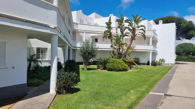a white house with a lawn in front of it at Apartamento Retama Golf in Chiclana de la Frontera