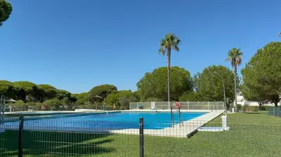an empty swimming pool with palm trees in the background at Apartamento Retama Golf in Chiclana de la Frontera