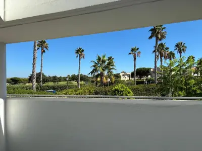 a window with palm trees in the background at Apartamento Retama Golf in Chiclana de la Frontera