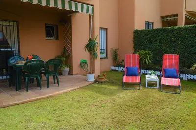 a patio with two chairs and a table in a yard at Bonito apartamento con jardín privado en Novo in Novo Sancti Petri
