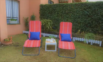 two chairs and a table in a yard at Bonito apartamento con jardín privado en Novo in Novo Sancti Petri