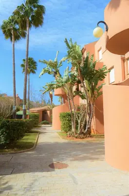 a street with palm trees and a building at Bonito apartamento con jardín privado en Novo in Novo Sancti Petri
