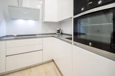 a kitchen with white cabinets and a black appliance at Apartamento Las Calas de Cadiz in Cádiz