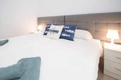 a bedroom with a white bed with blue pillows at Apartamento Las Calas de Cadiz in Cádiz