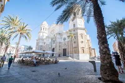 people sitting at tables in front of a church at Apartamento Las Calas de Cadiz in Cádiz