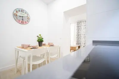 a dining room with a table and a clock on the wall at Apartamento Las Calas de Cadiz in Cádiz