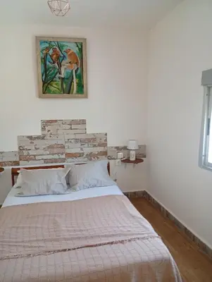 a bedroom with a bed and a painting on the wall at Casa del abuelo trujillo 2 in Conil de la Frontera