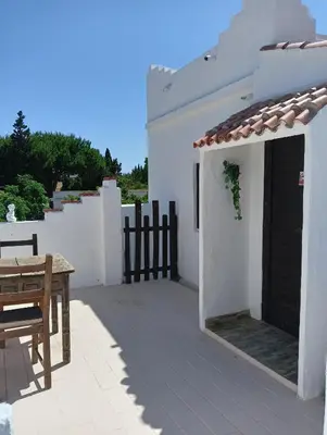 a white house with a table and a black door at Casa del abuelo trujillo 2 in Conil de la Frontera