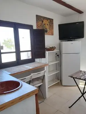 a kitchen with a desk with a tv and a refrigerator at Casa del abuelo trujillo 2 in Conil de la Frontera