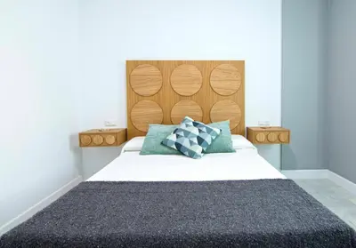 a bedroom with a large bed with a wooden headboard at El Patio del Sol, Apartamentos Living Sur in Sanlúcar de Barrameda