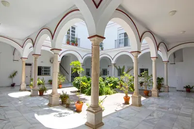 an empty building with columns and potted plants at El Patio del Sol, Apartamentos Living Sur in Sanlúcar de Barrameda
