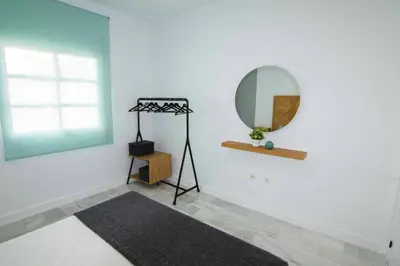 a white room with a mirror and a rug at El Patio del Sol, Apartamentos Living Sur in Sanlúcar de Barrameda