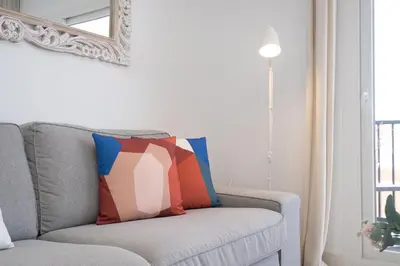a living room with a gray couch with a colorful pillow at SibsSanlucar Casa Manuela - Céntrico - Vistas Coto Doñana in Sanlúcar de Barrameda
