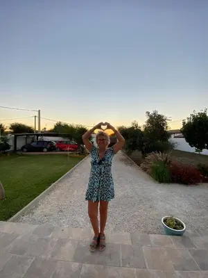 a woman standing on a sidewalk with her hands on her head at Villa Jaca azule in Chiclana de la Frontera