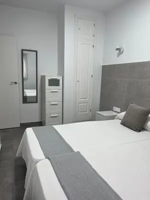 a bedroom with a large white bed and a mirror at Alojamientos La Menúa in Los Badalejos
