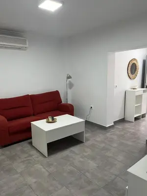a living room with a red couch and a white table at Alojamientos La Menúa in Los Badalejos
