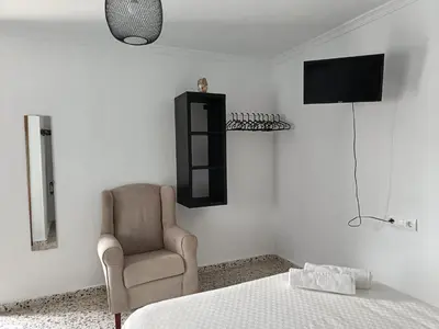 a bedroom with a bed and a chair and a television at Alojamientos La Menúa in Los Badalejos