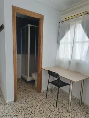 a table and a chair in a room with a toilet at Alojamientos La Menúa in Los Badalejos