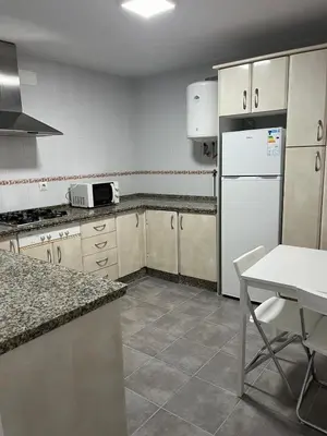 a kitchen with a white refrigerator and a table at Alojamientos La Menúa in Los Badalejos