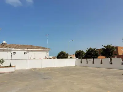 a white fence in front of a parking lot at Apartamento en Rota con piscina y parking junto al mar in Rota