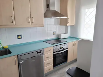 a kitchen with wooden cabinets and a blue counter top at Apartamento en Rota con piscina y parking junto al mar in Rota