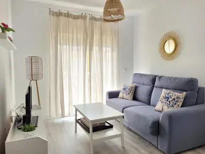 a living room with a blue couch and a table at Apartamento en Rota con piscina y parking junto al mar in Rota