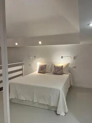 a white bedroom with a white bed with two pillows at Loft EL DUQUE in Sanlúcar de Barrameda