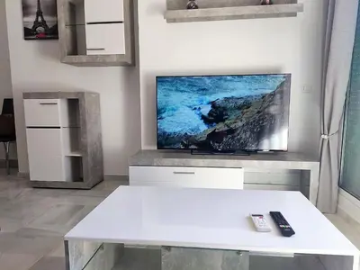 a living room with a white table and a tv at LAS INFANTAS HOME in Sanlúcar de Barrameda