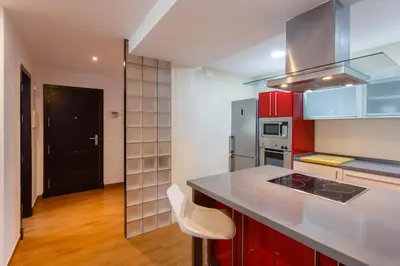 a kitchen with red cabinets and a counter top at El Velero en la playa Victoria Grupo AC Gestion in Cádiz