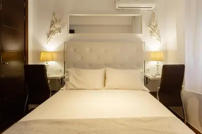 a bedroom with a large white bed with two desks at El Velero en la playa Victoria Grupo AC Gestion in Cádiz