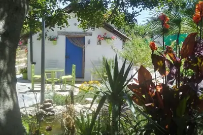 a garden with a house with a blue door at Vivienda Rural La choza in Jerez de la Frontera