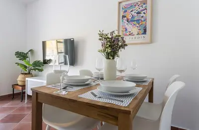 a dining room table with white chairs and a table with glasses at Azvalia - Atarazana in El Puerto de Santa María
