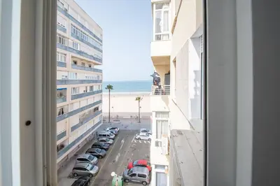 a view from a window of a parking lot and the beach at Apartamento Sunset Cádiz in Cádiz