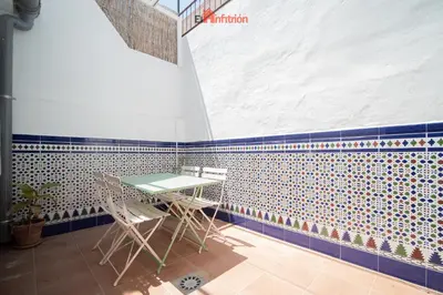 a table and chairs in a room with a tiled wall at El Anfitrión - La Cómoda in Sanlúcar de Barrameda