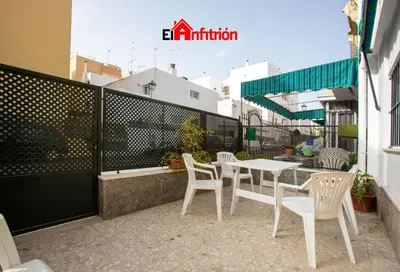 a patio with white chairs and a table and a fence at El Anfitrión - La Cómoda in Sanlúcar de Barrameda