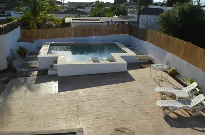 a patio with a swimming pool with chairs and a table at La Estrella - piscina privada in Chiclana de la Frontera