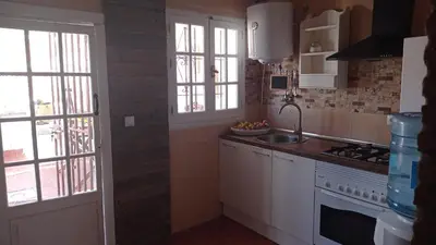 a kitchen with white cabinets and a sink and windows at La Estrella - piscina privada in Chiclana de la Frontera