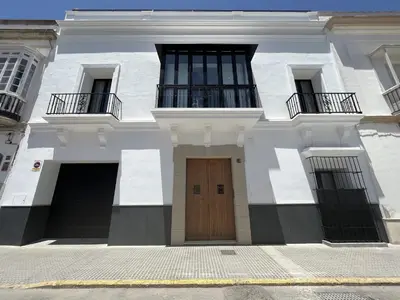 a white building with a wooden door and two balconies at CAMASanlúcar in Sanlúcar de Barrameda