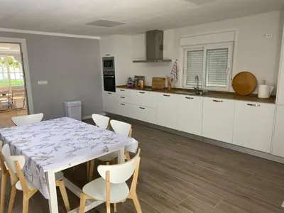 a kitchen with a table and chairs in a room at La Ranaverde, piscina y playa in Chiclana de la Frontera