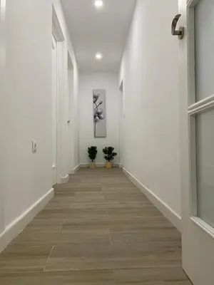 a hallway with white walls and wood floors and two plants at La Ranaverde, piscina y playa in Chiclana de la Frontera