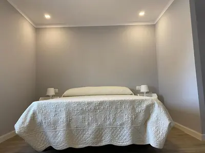 a bedroom with a bed with a white bedspread and two lamps at La Ranaverde, piscina y playa in Chiclana de la Frontera