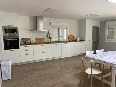 a kitchen with white cabinets and a table with chairs at La Ranaverde, piscina y playa in Chiclana de la Frontera