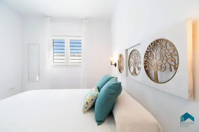 a white bedroom with a bed with blue pillows at Sauz B in Chiclana de la Frontera