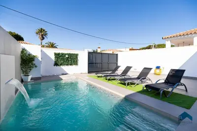 a swimming pool with chairs and a water fountain at Sauz B in Chiclana de la Frontera