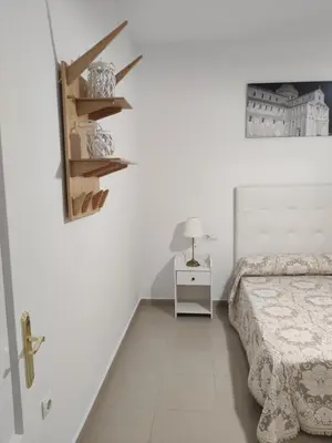 a white bedroom with a bed and a lamp on a shelf at Apartamento Cristina centro in Sanlúcar de Barrameda